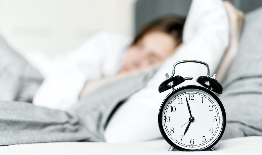 alarm clock with a woman sleeping in the background