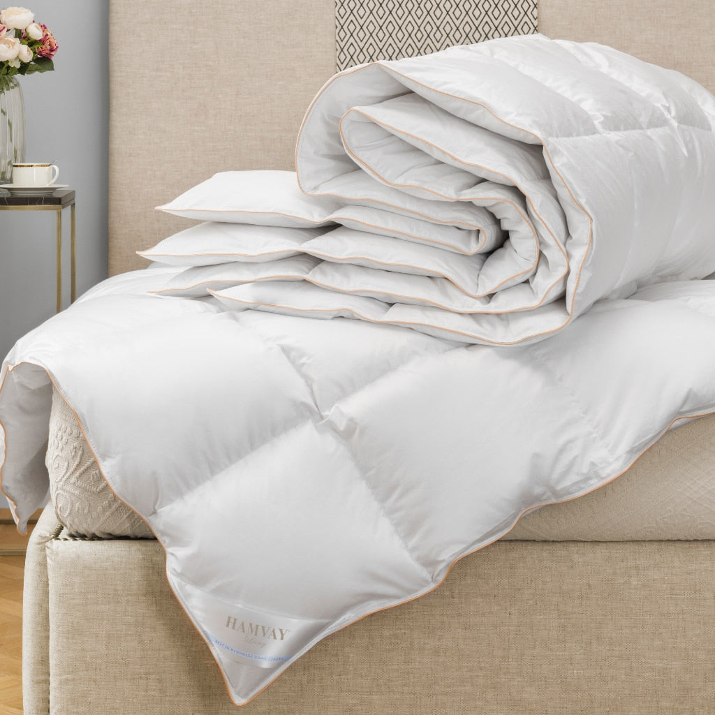 two white goose down comforters folded on bed