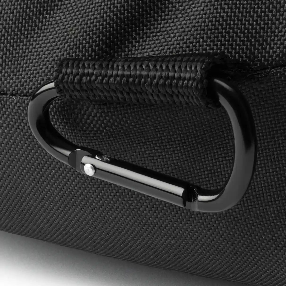 Close-up of a black carabiner attached to a textured black surface