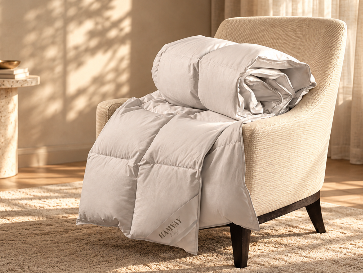 A light beige quilted comforter is draped over a matching upholstered armchair in a warm, sunlit room. 