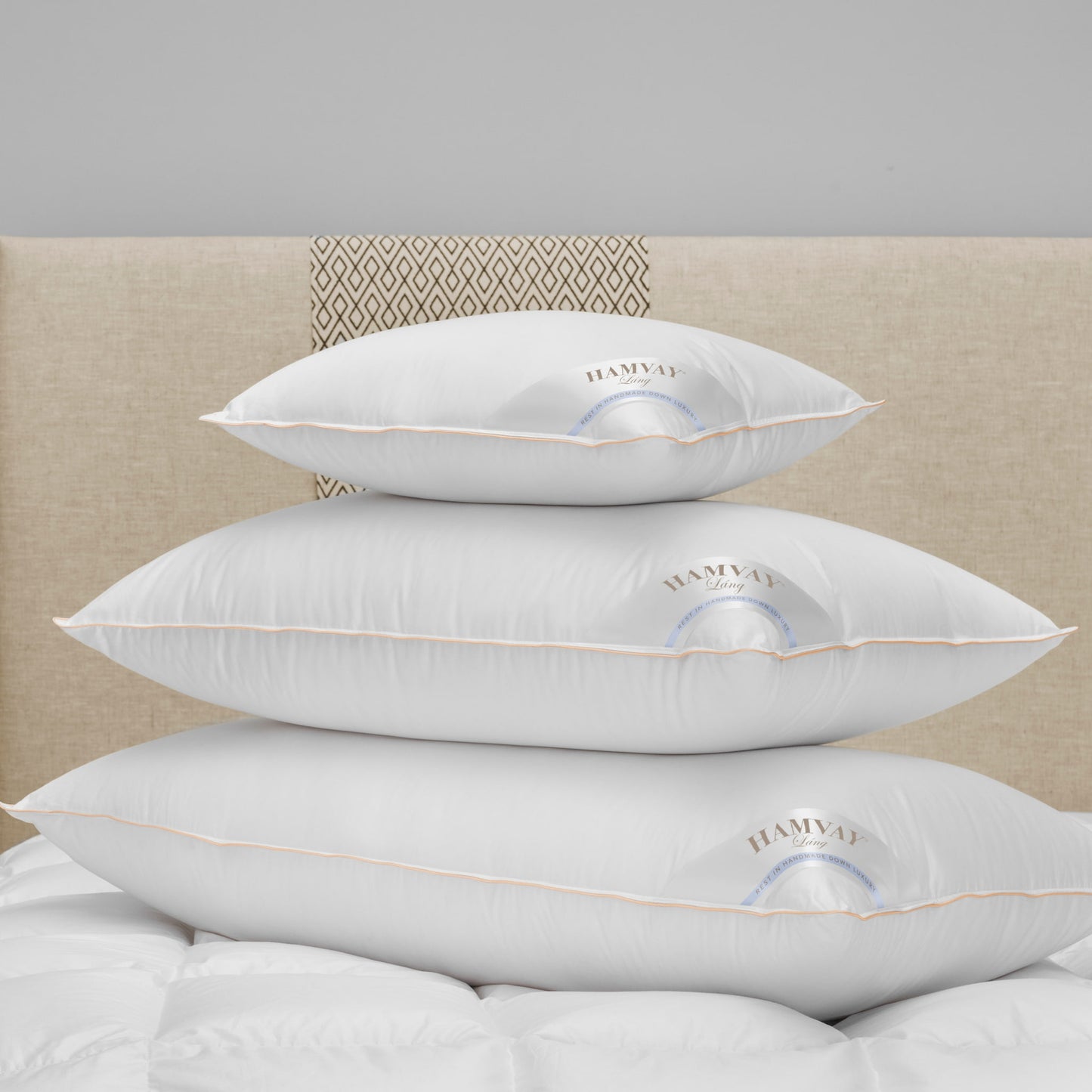 3 sizes of soft luxurious Hungarian goose down pillows on top of each other on a beige bed