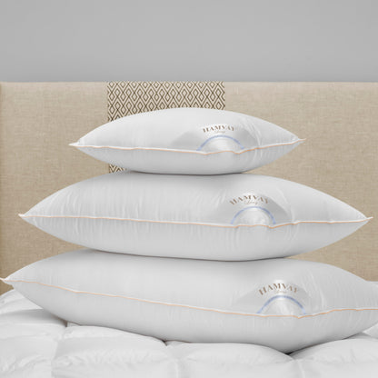 3 sizes of soft luxurious Hungarian goose down pillows on top of each other on a beige bed