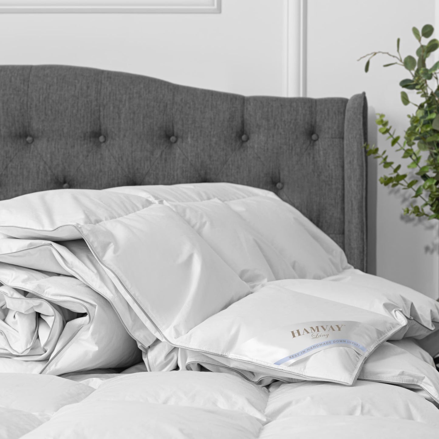 A luxurious Hungarian goose down comforter losely spread over a grey bed