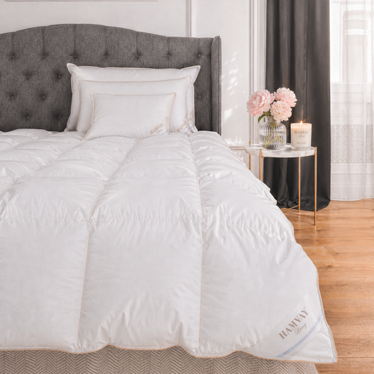 White comforter on a bed with a gray headboard and decorative elements in a bedroom.