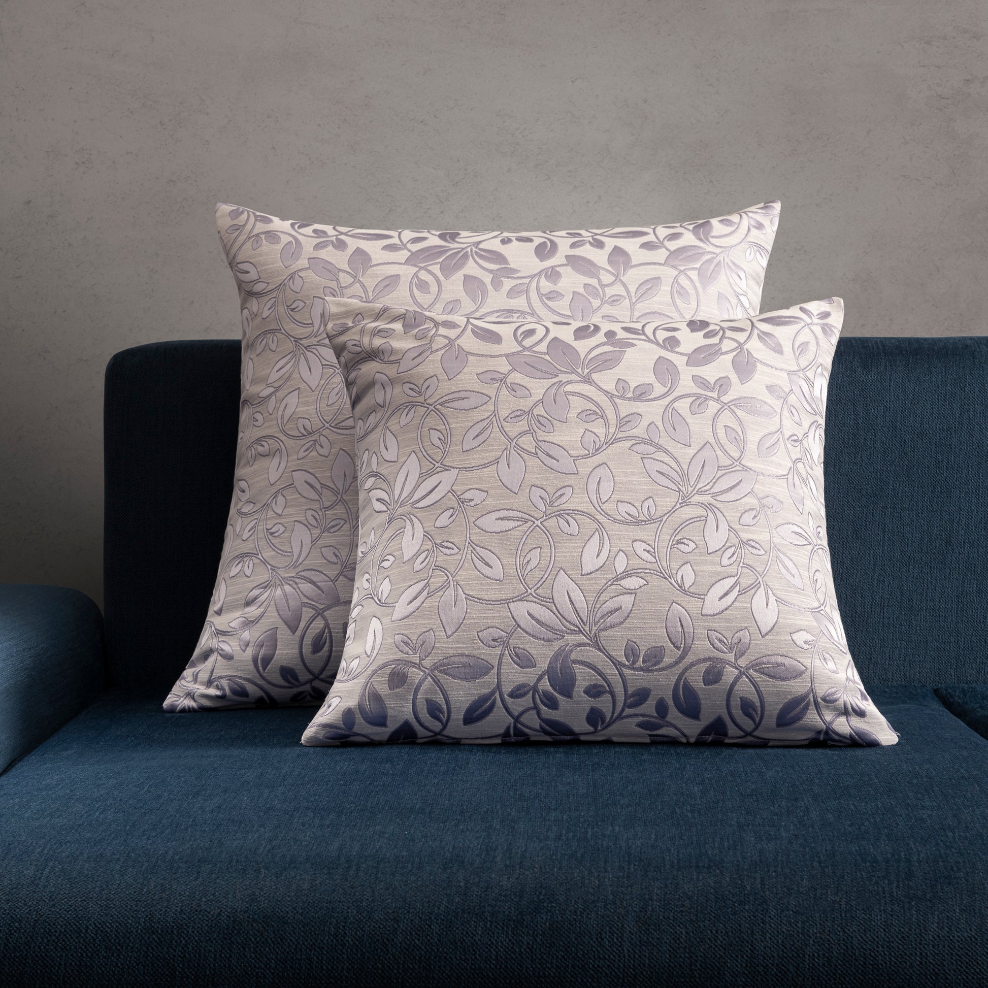 2 purple floral decorative pillow placed on a blue sofa